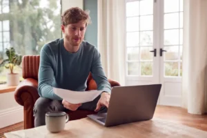 man sitting on armchair at home with laptop paying 2024 10 22 08 37 34 utc